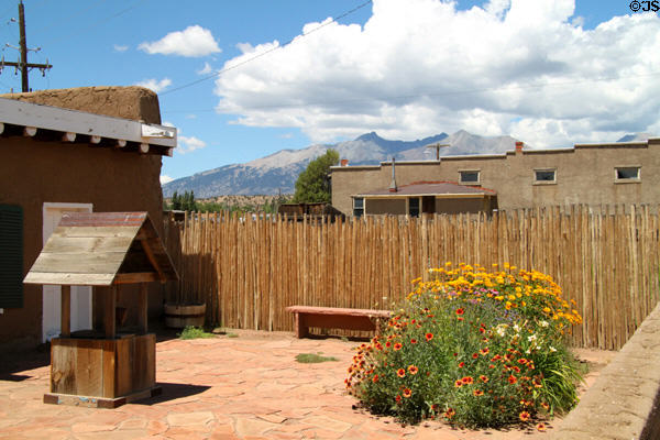 Flowers in Fort Garland stockade against mountains in distance. Fort Garland, CO.