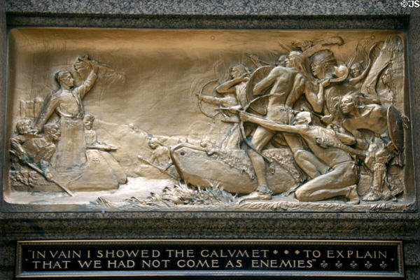 Bronze relief of Marquette holding up peace pipe to hostile native Americans 