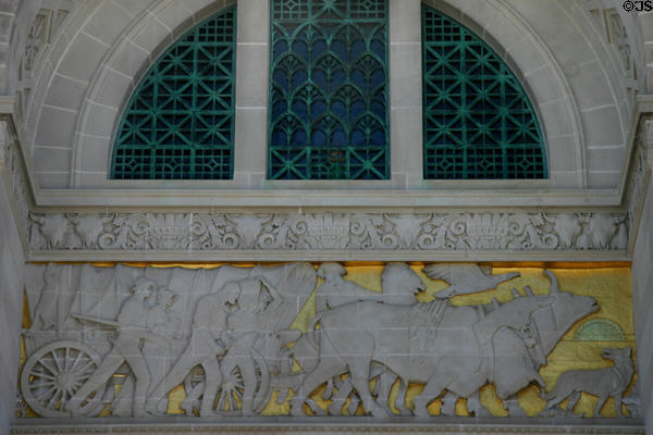 Relief of pioneers moving west by oxen-drawn Conestoga wagon on Nebraska State Capitol. Lincoln, NE.