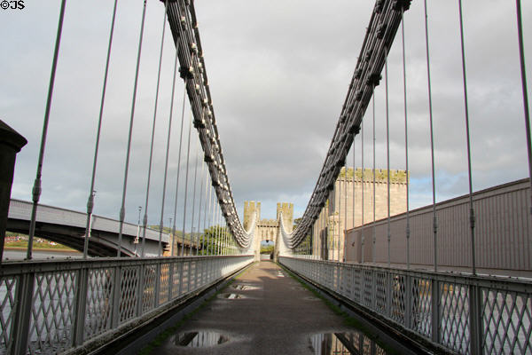 View down Telford suspension bridge towards east river bank with Stephenson's tube railway bridge (1846-48) & road bridge (1958), known as Three Bridges, on either side. Conwy, Wales.