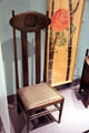 Oak side armchair with horsehair seat by Charles Rennie Mackintosh originally designed for Miss Cranston`s Argyle Street Tea Rooms of Glasgow beside rose banner by Mackintosh & Margaret MacDonald for exhibit in Turin, Italy at Royal Ontario Museum. Toronto, ON.