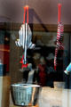 Fanciful shop window showcasing stuffed chickens over portable charcoal grill. Augsburg, Germany.