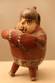 Nazca culture ceramic stirrup-spout bottle of fisherman playing flute, with a net on his back from Peru at Museum of America. Madrid, Spain.