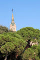 Tower of Gaudi House over trees of Parc Güell. Barcelona, Spain.