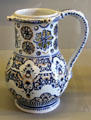 Rouen-made earthenware puzzle jug painted blue & red at Rouen Ceramic Museum. Rouen, France.