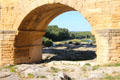 View of Gard River through aqueduct bridge arch at Pont du Gard. Nimes, France.