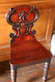 Side chair with scrolled back carved with archer's arm in entrance hall at Haddo House. Methlick, Scotland.