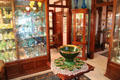 Display cases with glass collection around emerald green punchbowl by United States Glass Co. of Glassport, PA at Historical Glass Museum. Redlands, CA.