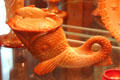 Glass dolphin with fish cover dish in orange by Greentown Glass or reproduction at Historical Glass Museum. Redlands, CA.