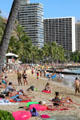Sitting on sand on beach in Waikiki. Waikiki, HI.
