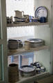 Ceramic dishes on shelves placed across window frame at Sauer-Beckmann Farmstead. Stonewall, TX.