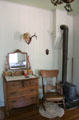 Bedroom with dresser, rocking chair & heating stove at Sauer-Beckmann Farmstead. Stonewall, TX.