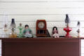 Oil lamps, mantle clock & dolls in Bell House at Pioneer Farms. Austin, TX.