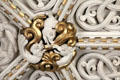 Detail of gilded medallion with intertwined sculpted plaster figures on ornate ceiling in Library at Penrhyn Castle. Bangor, Wales.