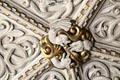Detail of gilded medallion with intertwined sculpted plaster figures on ornate ceiling in Library at Penrhyn Castle. Bangor, Wales.