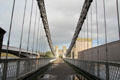 View down Telford suspension bridge towards east river bank with Stephenson's tube railway bridge & road bridge , known as Three Bridges, on either side. Conwy, Wales.