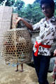 Bangli temple keeper with cock in basket. Bali, Indonesia.